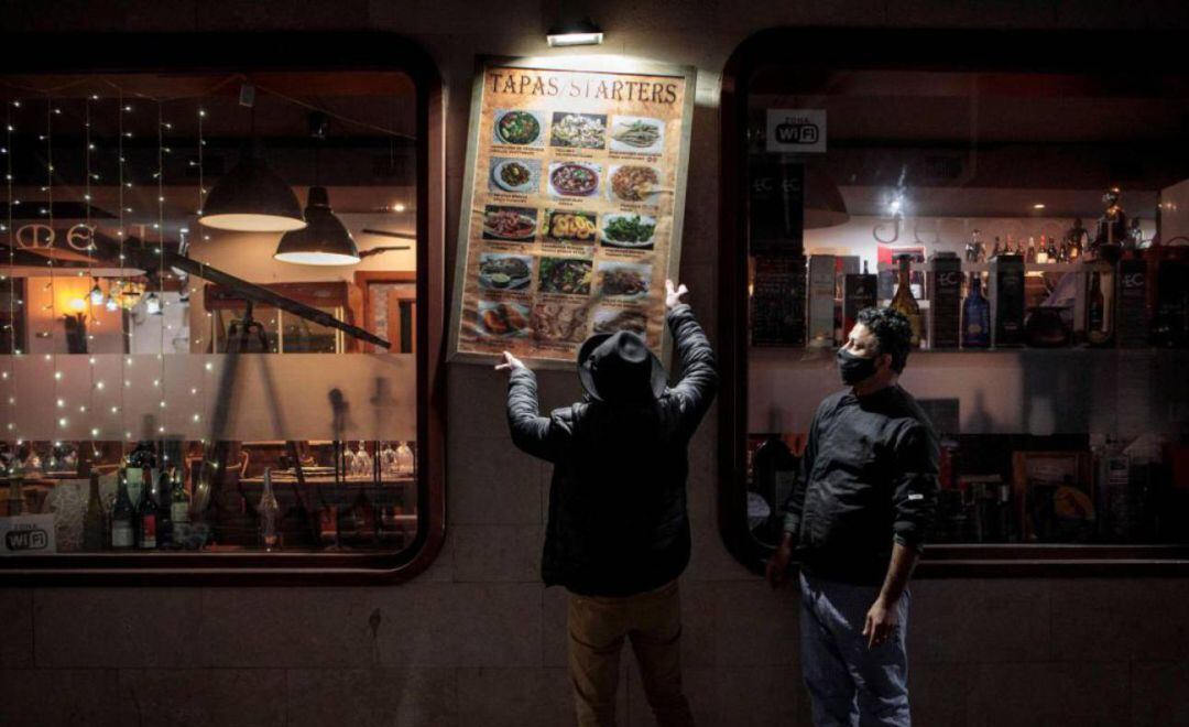 Unos trabajadores de un restaurante del centro de València recogen la terraza el día que se aplicó en la Comunitat Valenciana las nuevas medidas contra la pandemia de coronavirus