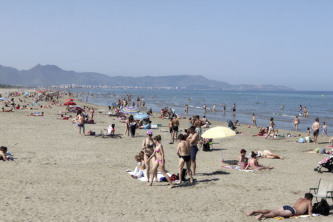 Bañistas en las playas de Castelló con Benicàssim y el desert de les Palmes al fondo