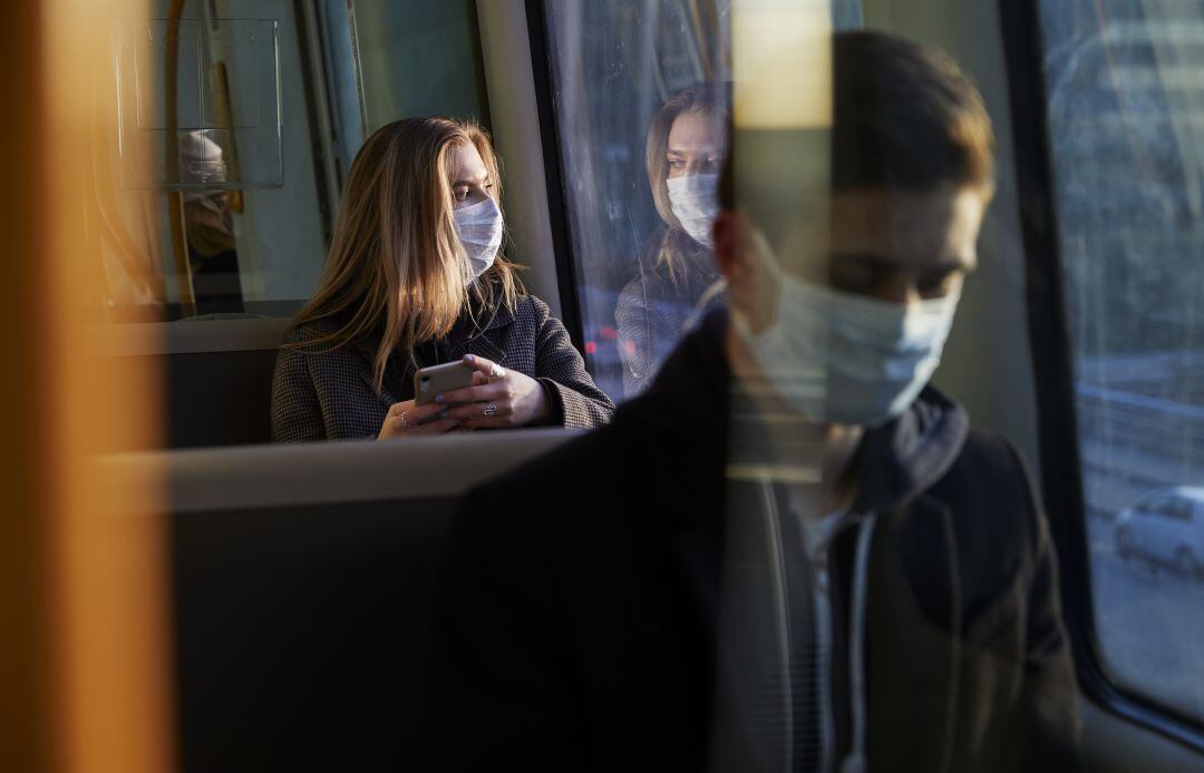 Jóvenes con mascarilla en el transporte público.