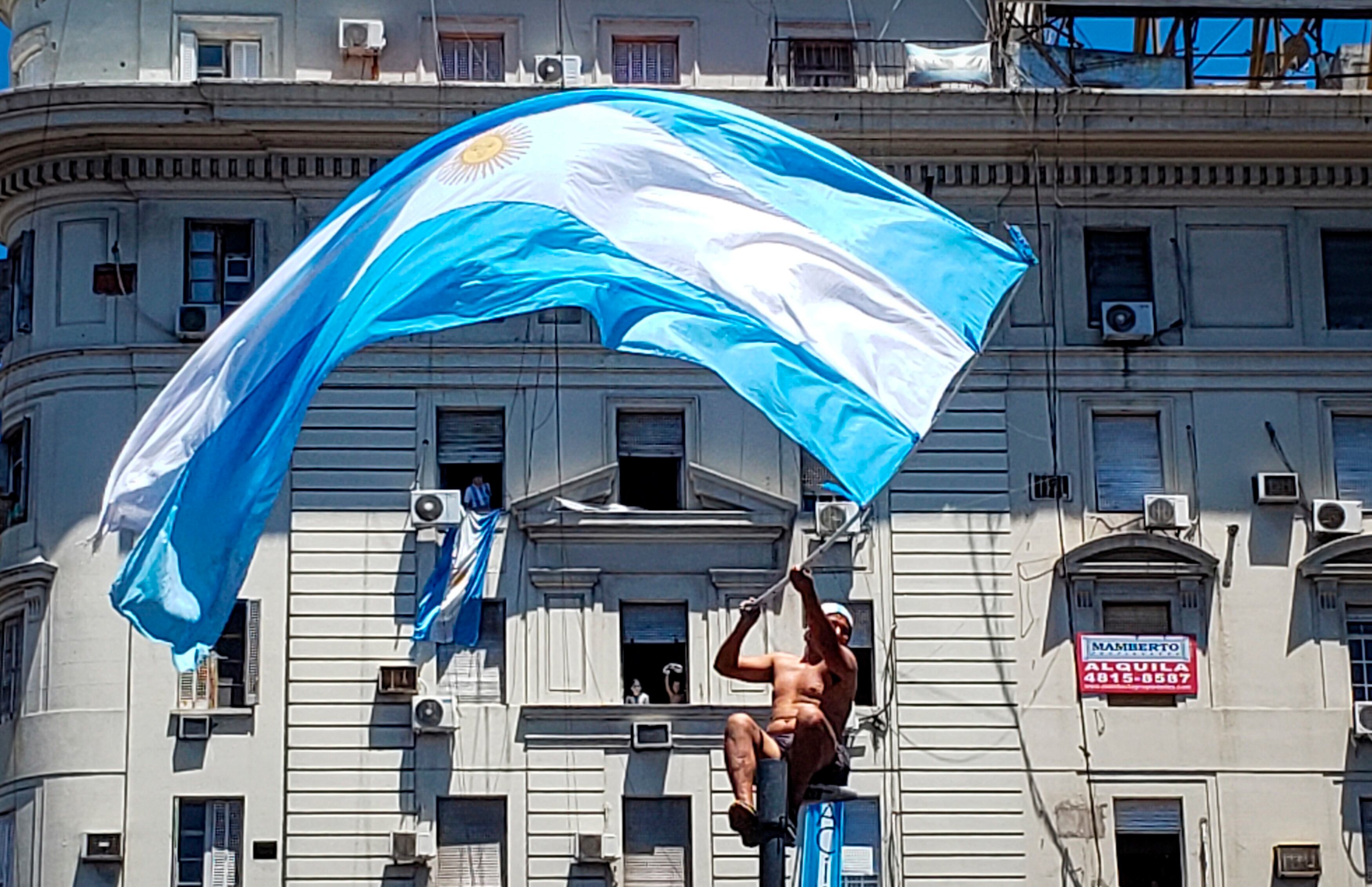 AMDEP9850. EZEIZA (ARGENTINA), 20/12/2022.- Un hincha de Argentina agita una bandera en la celebración hoy, de la victoria de la selección argentina en el Mundial de Qatar 202, en Buenos Aires (Argentina). Argentina se proclamó campeona del mundo tras ganar en la tanda de penaltis (4-2) a Francia, después del empate 3-3 en los 120 minutos de juego. EFE/ Raúl Martínez
