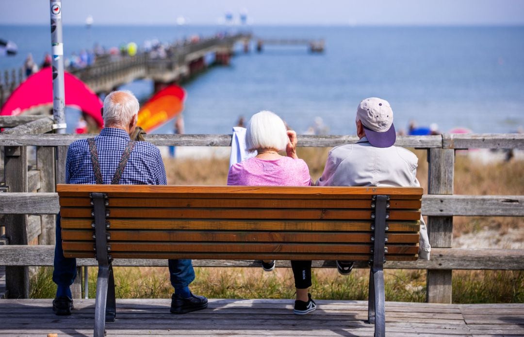 Personas mayores disfrutan del paisaje frente al mar.