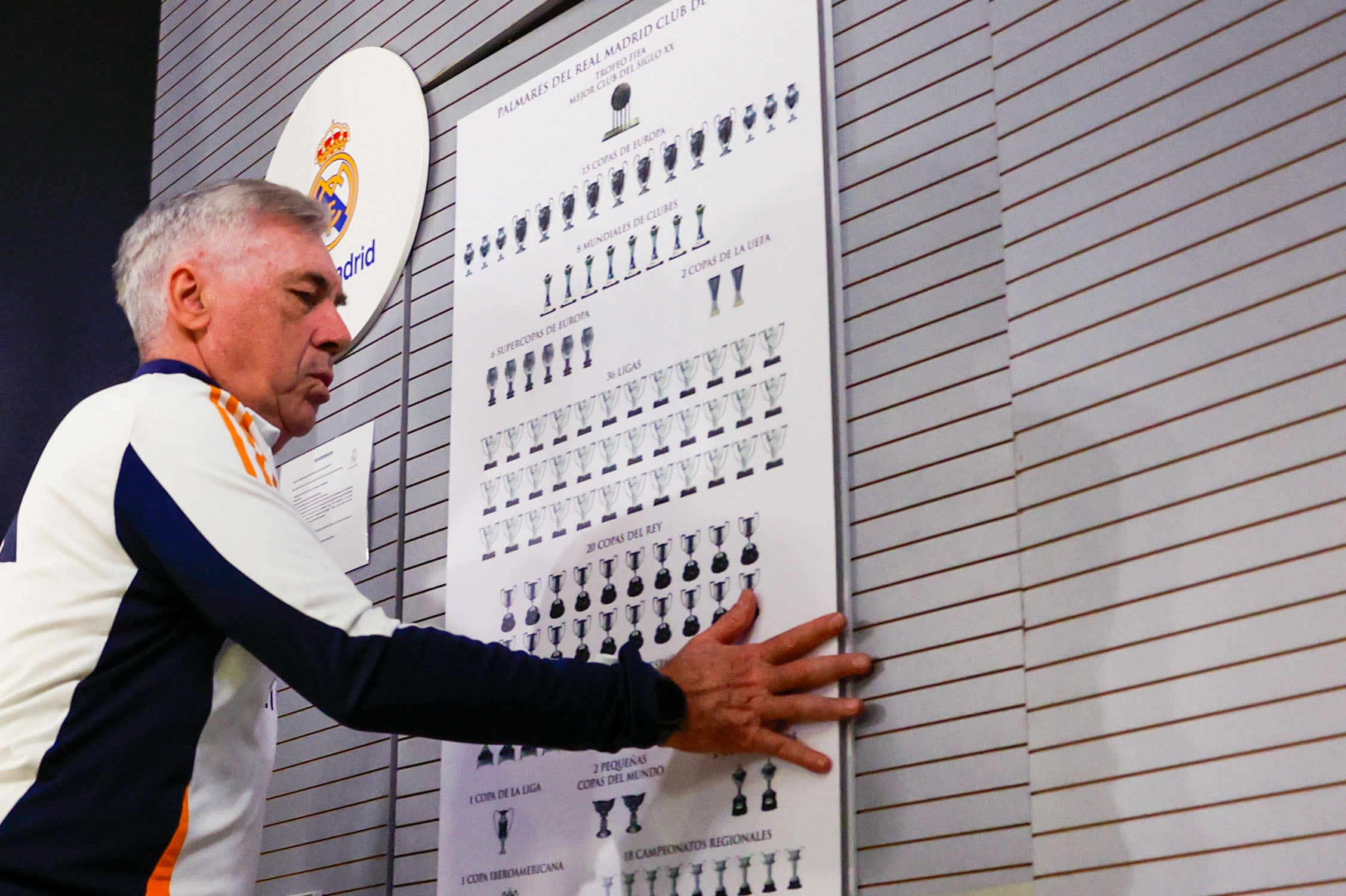 El técnico Carlo Ancelotti junto a un cartel con todos los trofeos del Real Madrid