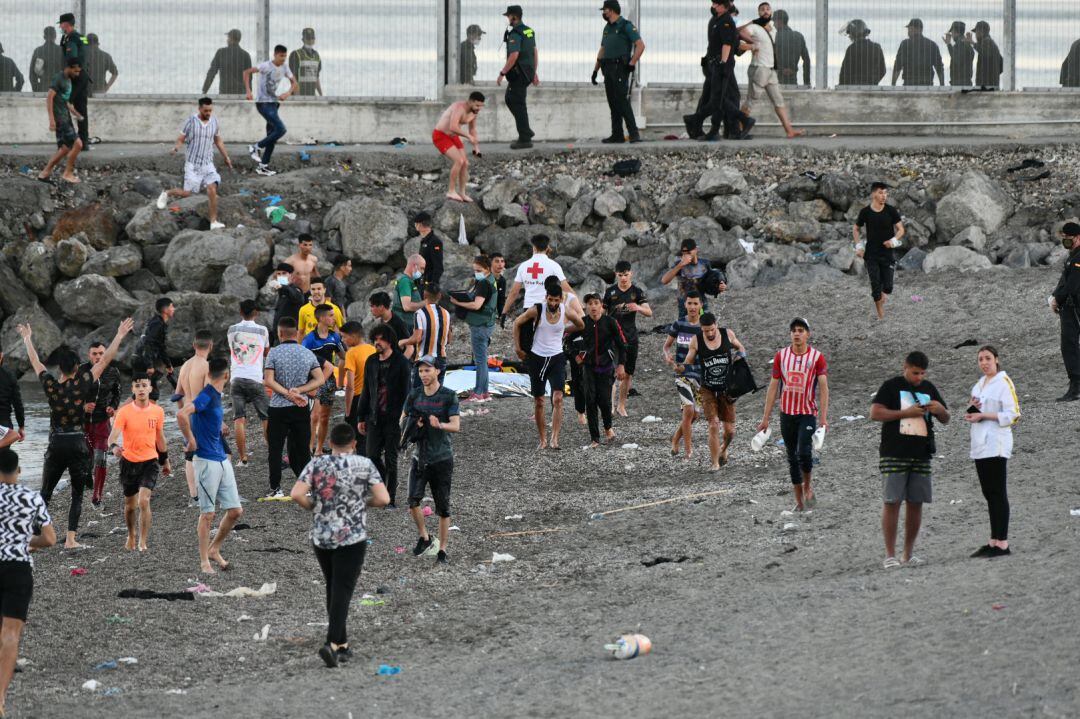 Personas migrantes caminan por la playa del Tarajal