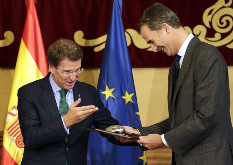 GRA095. SANTIAGO DE COMPOSTELA, 06/10/2015.- El rey Felipe VI recibe una placa conmemorativa y el título de embajador de honor del Camino de Santiago por su promoción de este itinerario cultural europeo, de manos del presidente de la Xunta, Alberto Núñez Feijóo (i), esta mañana en Santiago de Compostela. EFE/Lavandeira jr