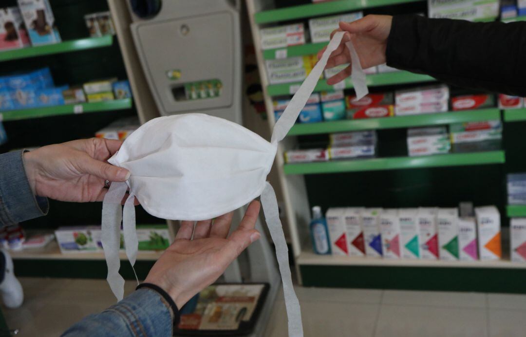 Dos personas sujetan una mascarilla.