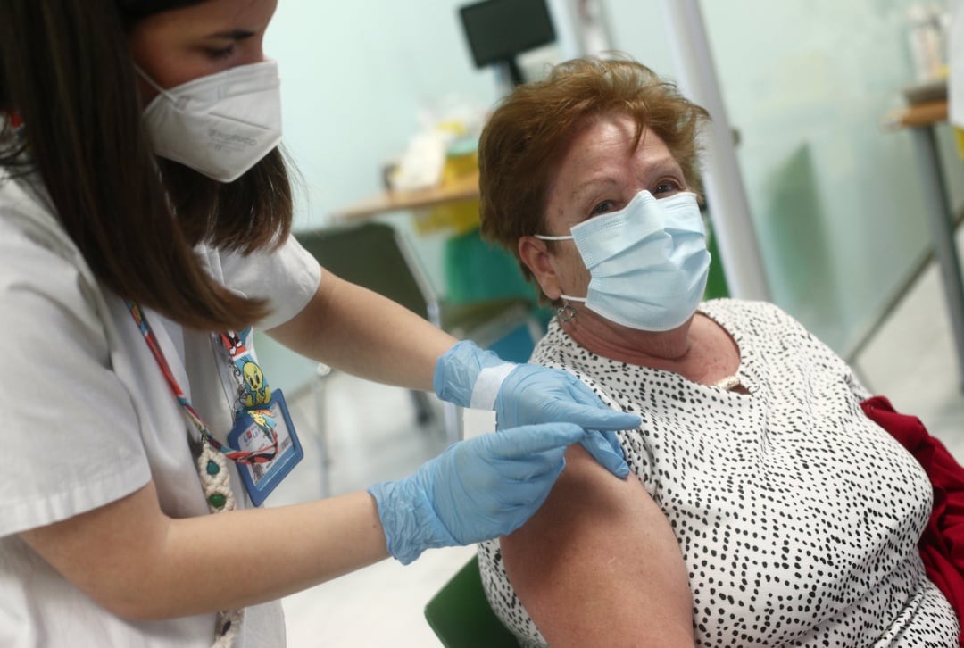 Una sanitaria inocula la primera dosis de la vacuna a una madrileña en un hospital de la capital