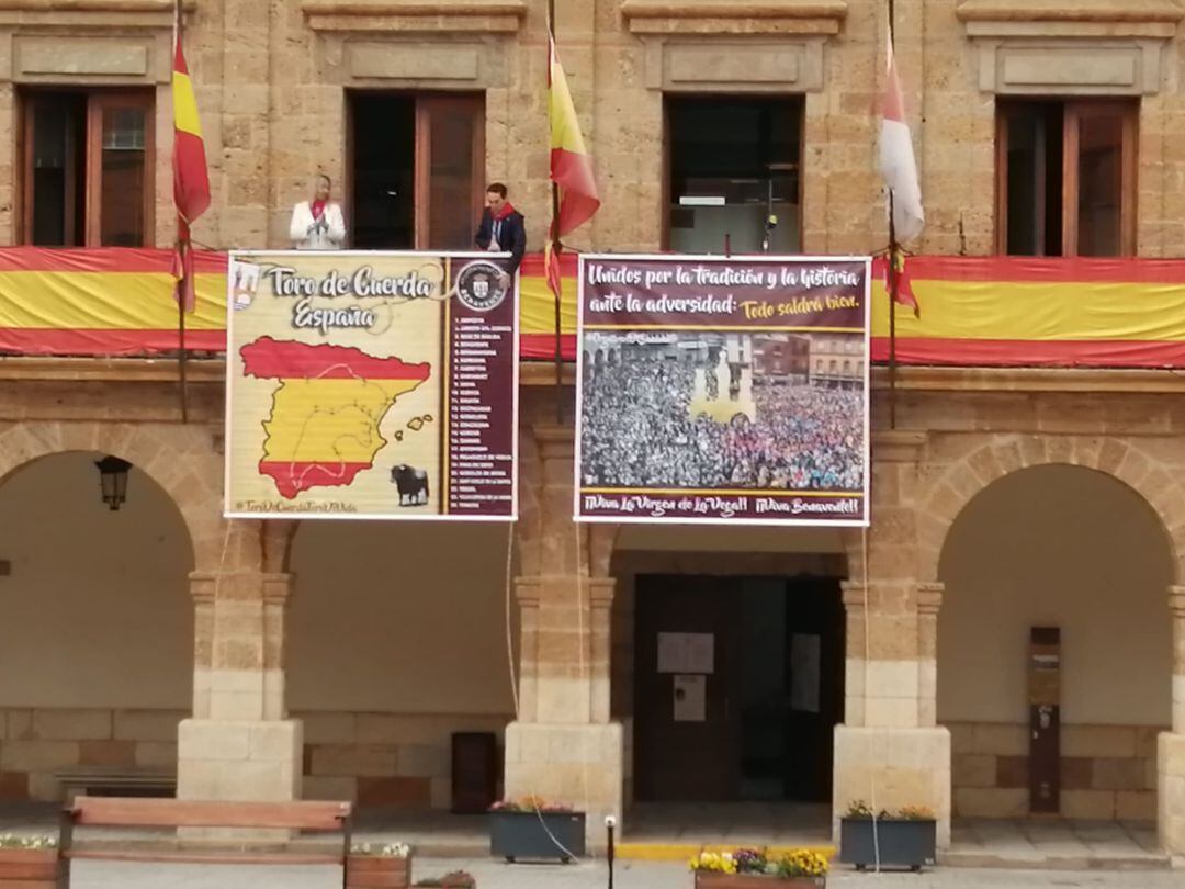 La concejala de Fiestas, Patricia Martín, y el alcalde de Benavente, Luciano Huerga, colocan las pancartas en el balcón del ayuntamiento