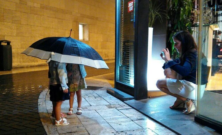 Dos niñas se fotografían bajo la lluvia caída este sábado en Murcia