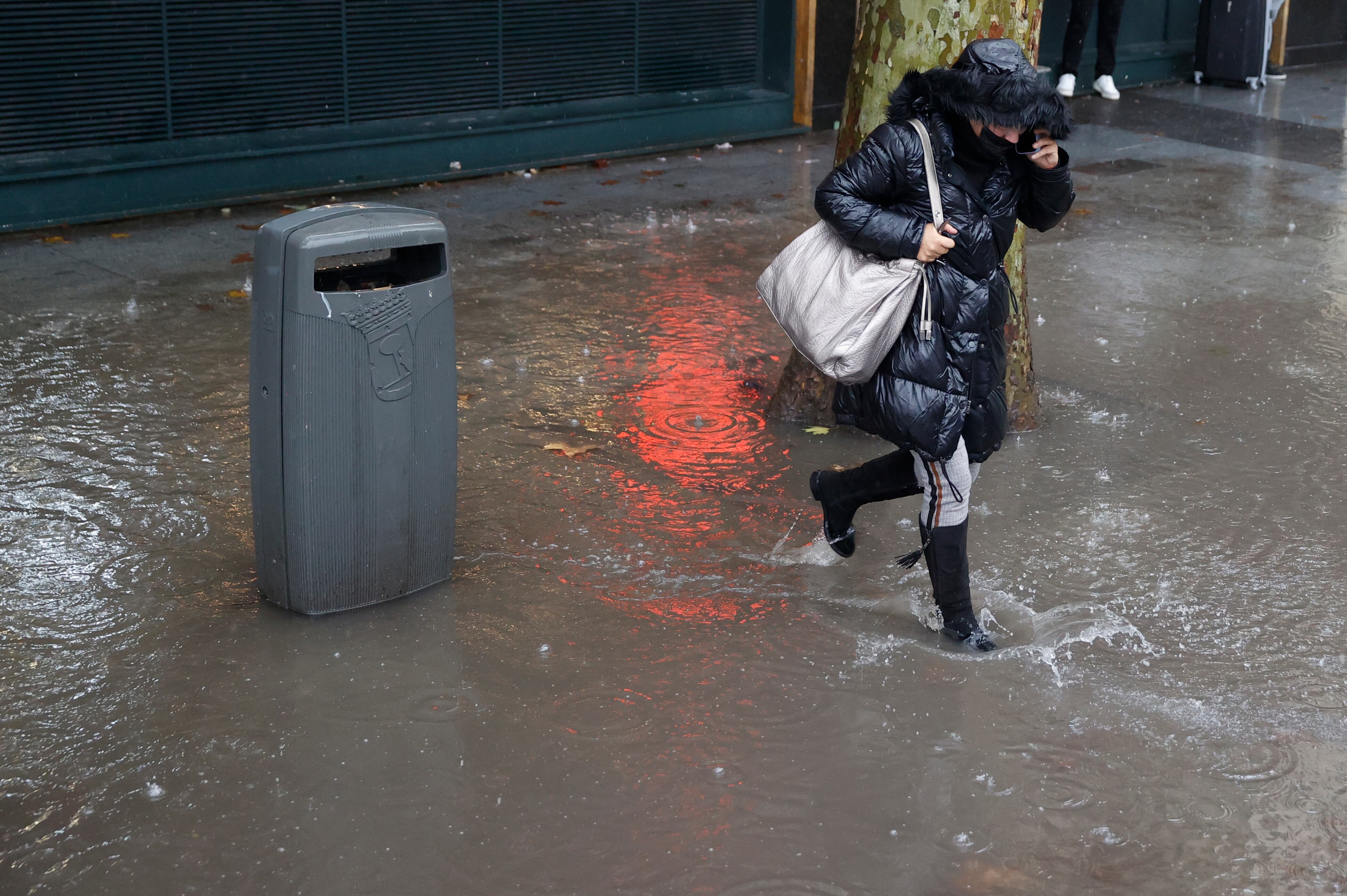 MADRID, 13/12/2022.- Una mujer corre para protegerse de la lluvia que se registra este martes en Madrid. La Agencia Estatal de Meteorología (Aemet) anuncia que la borrasca Ifraín dejará este martes en la Comunidad de Madrid lluvias débiles al principio del día, que se irán generalizando desde el oeste y serán más persistentes en la mitad sur de la provincia. EFE/MARISCAL
