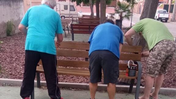 Vecinos de Medina del Campo lijando y pintando los bancos de su barrio