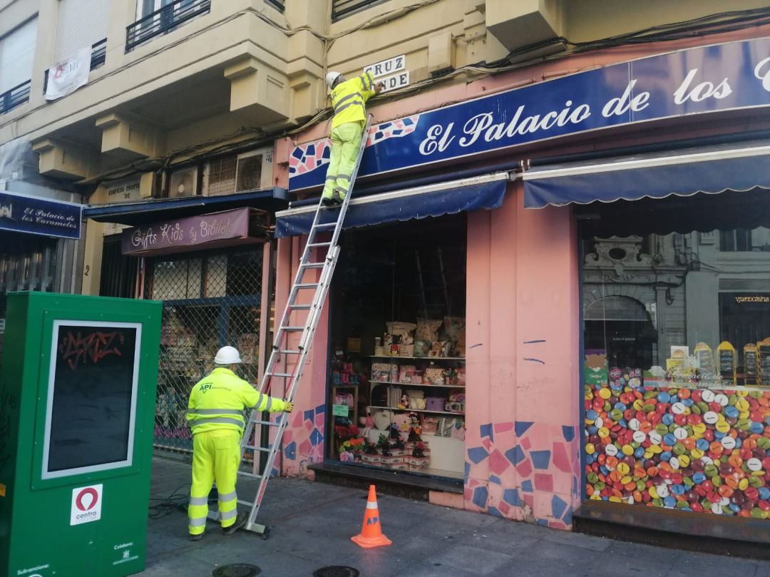 Operarios colocan el nuevo rótulo en la calle Cruz Conde