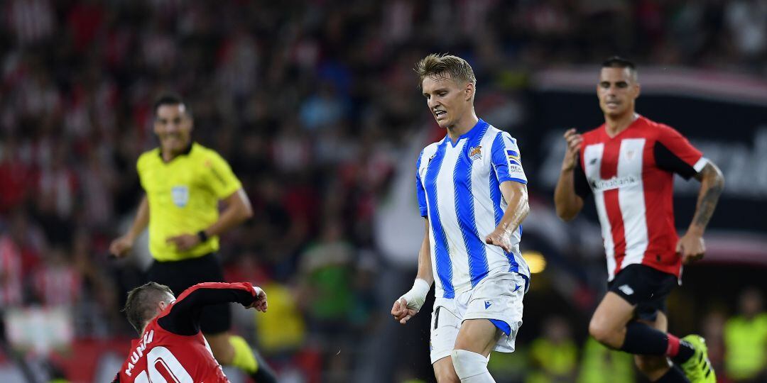 Odegaard trata de llevarse la pelota ante Muniain y Dani García