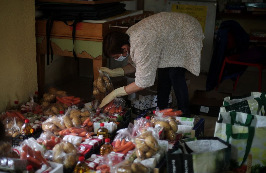 Una vecina voluntaria de la Red de Cuidados de Moratalaz prepara cestas de comida para repartir entre los más necesitados en el local de la Asociación APOYO.  