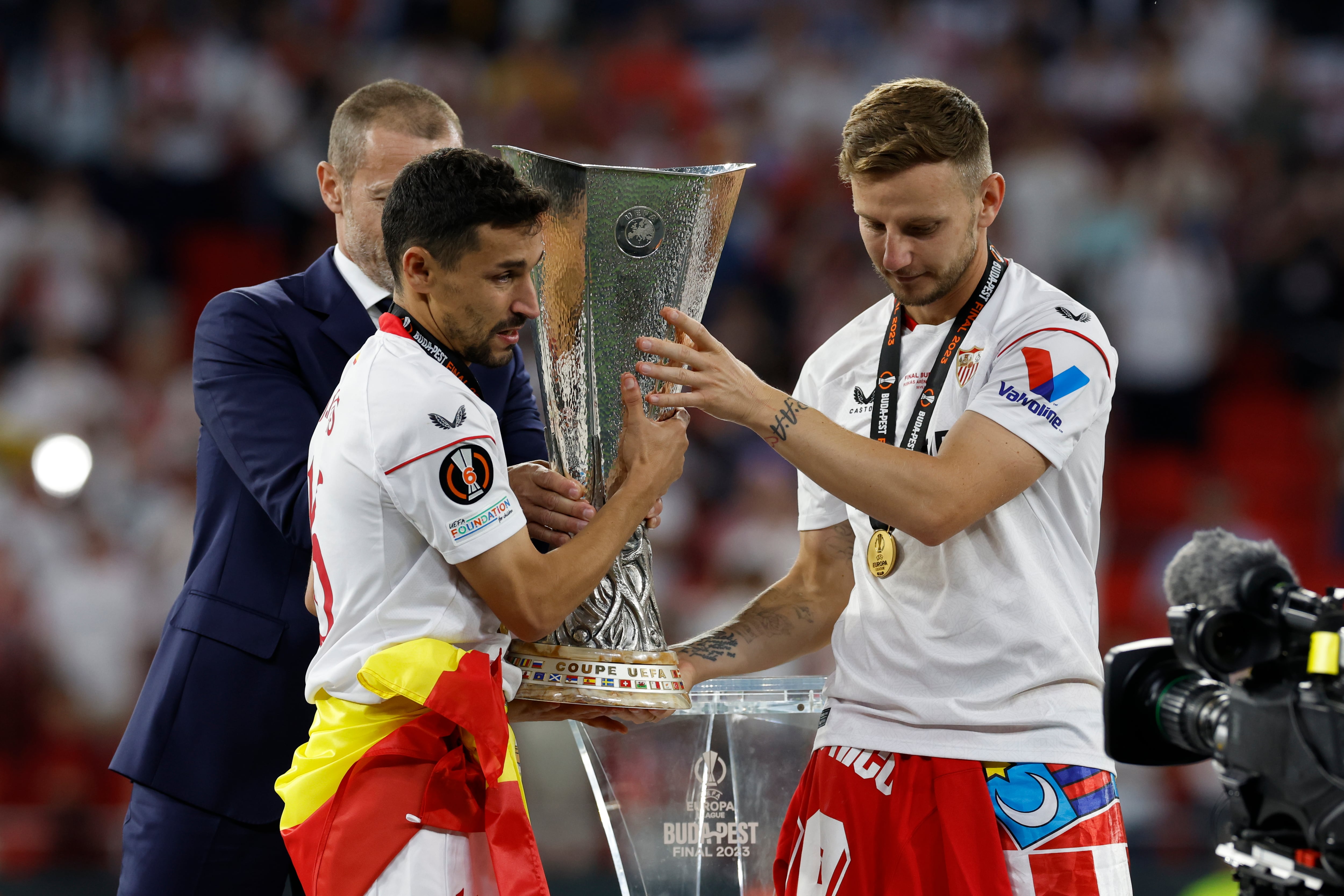 BUDAPEST (HUNGRÍA), 31/05/2023.- Los jugadores del Sevilla, Jesús Navas (i) y el croata Ivan Rakitic, reciben el trofeo conseguido en la final de la Europa League tras derrotar a la Roma en la tanda de penaltis del encuentro que han disputado este miércoles en el Puskas Arena de Budapest (Hungría). EFE/ Julio Muñoz.
