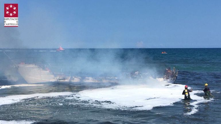 Varios efectivos de bomberos tratan de apagar las llamas de un barco accidentado en la costa entre Alcossebre y Torreblanca