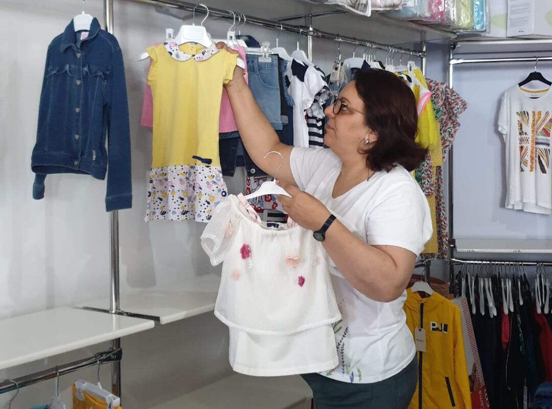 Trabajadora colocando ropa en una tienda.