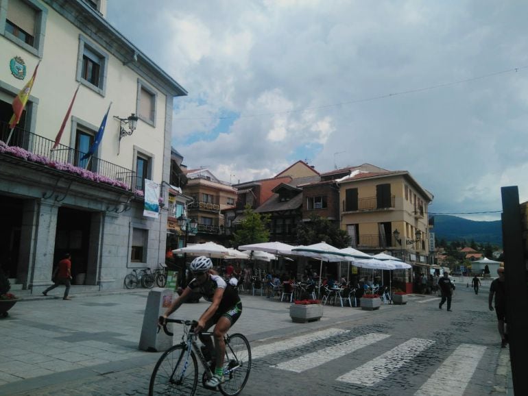 Una cicista pasa por la puerta del Ayuntamiento de Cercedilla