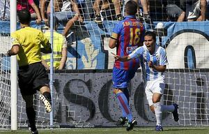 El delantero argentino del Málaga Javier Saviola celebra su gol, el primero de su equipo, en presencia del defensa del Levante, Sergio Ballesterosdurante el partido correspondiente a la cuarta jornada de la Liga de Primera División disputado en el estadio