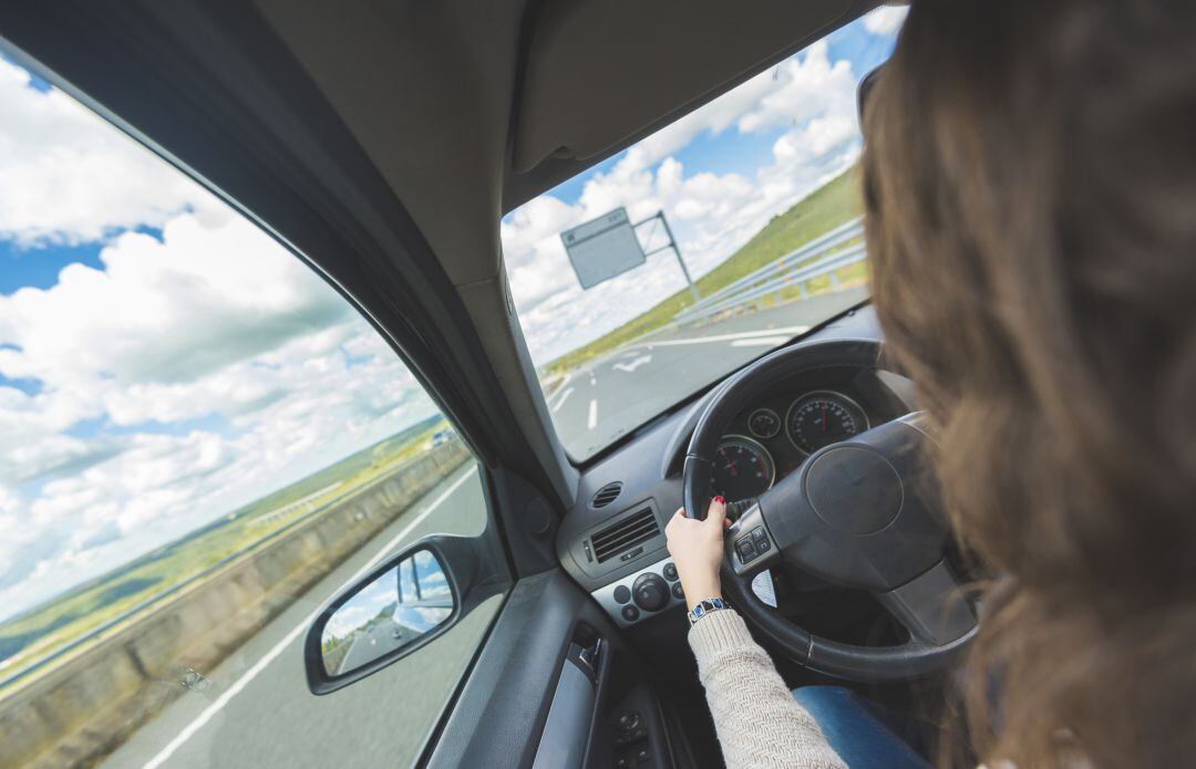 Una mujer conduce un vehículo por la carretera.