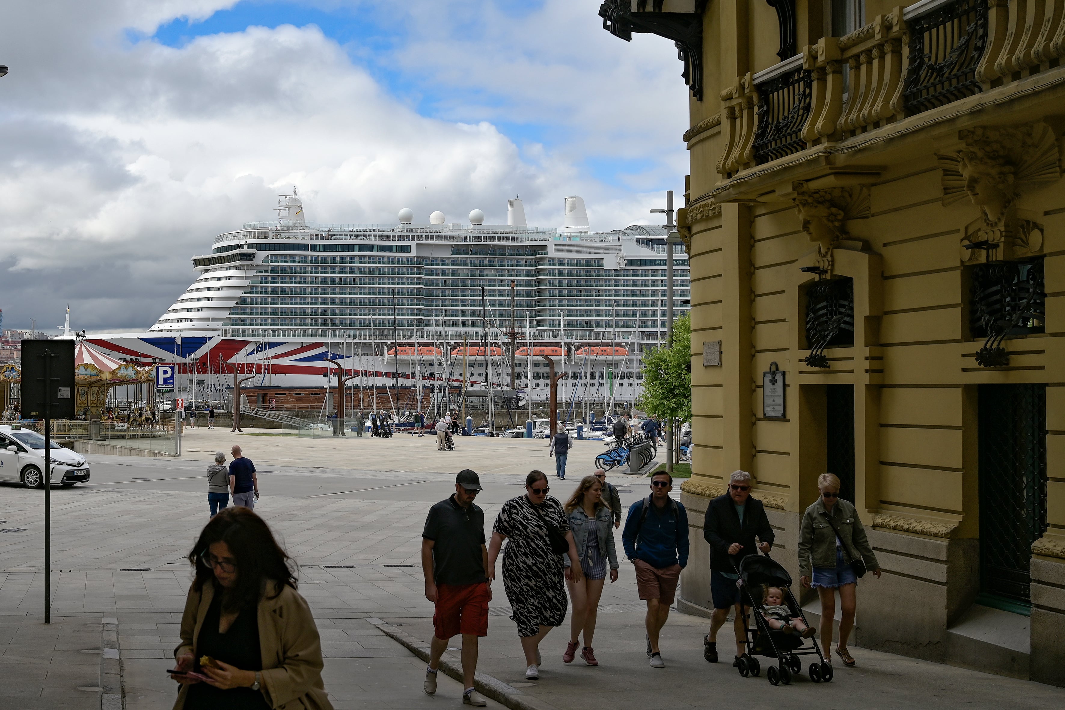 A CORUÑA, 31/08/2025.- Varios turistas pasean por Puerta Real ante un barco de cruceros atracado en el Puerto de A coruña. El turismo de cruceros no deja de crecer en la ciudad de A Coruña, pero la duda es qué hacen los pasajeros al desembarcar: monumentos, compras o Santiago de Compostela son las principales ofertas. EFE/ Moncho Fuentes
