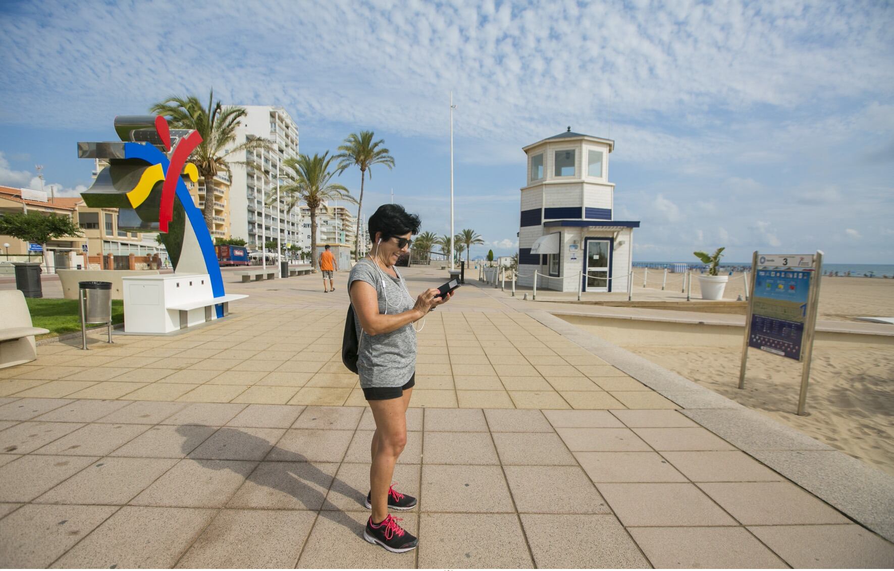 Una mujer consulta su teléfono, conectada al WiFi de la Playa de Gandia.