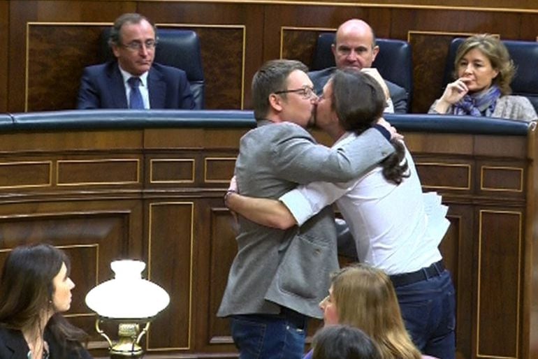 El líder de Podemos, Pablo Iglesias (d), y el de En Comú Podem, Xavier Doménech, se besa en los labios al término de la intervención del diputado catalán.