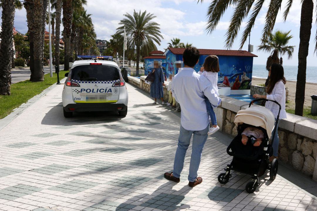 Un coche de la Policía Local de Málaga informa a viandantes en el paseo marítimo de La Malagueta en el primer día de paseo con niños