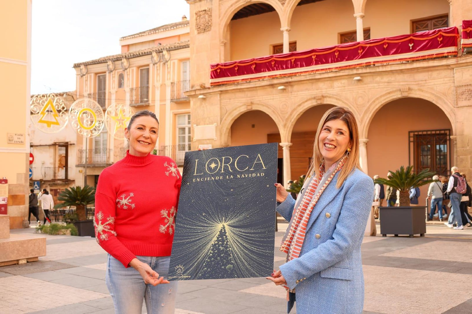 María de las Huertas García, edil de Festejos y Rosa María Medina, edil de Desarrollo Local con el cartel de la Navidad 2024