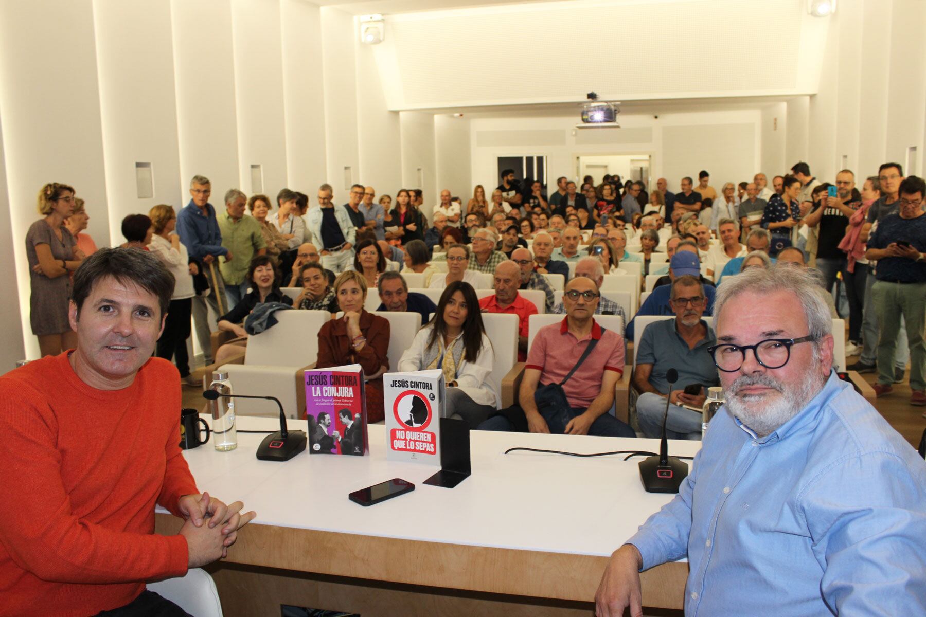 Jesús Cintora y Xavi Cortes, patrono de la Fundación Mutua Levante, con el auditorio repleto de público al fondo