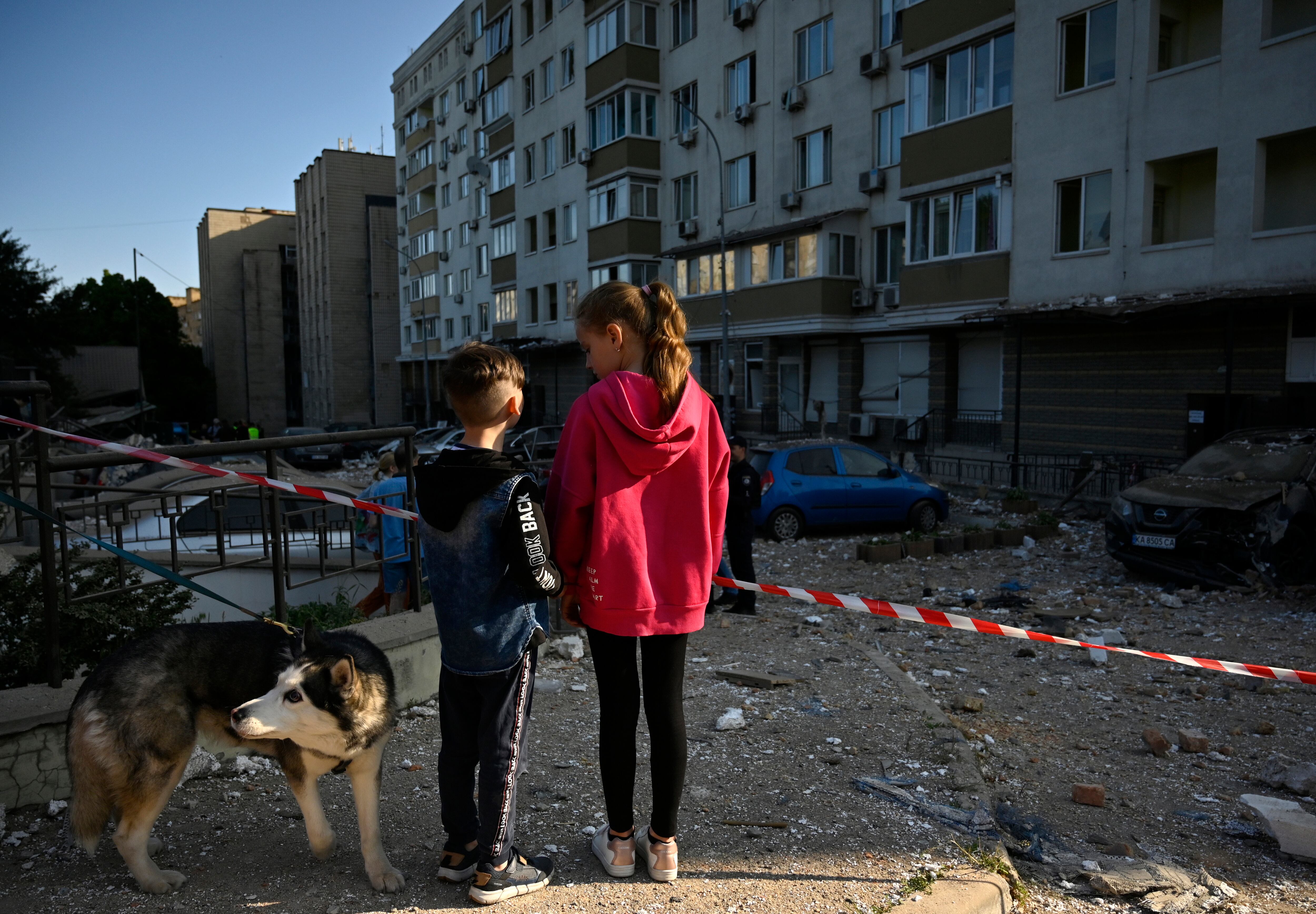 Dos menores ucranianos observan los estragos que causaron la caída de varios misiles sobre un edificio residencial de Kiev, capital de Ucrania