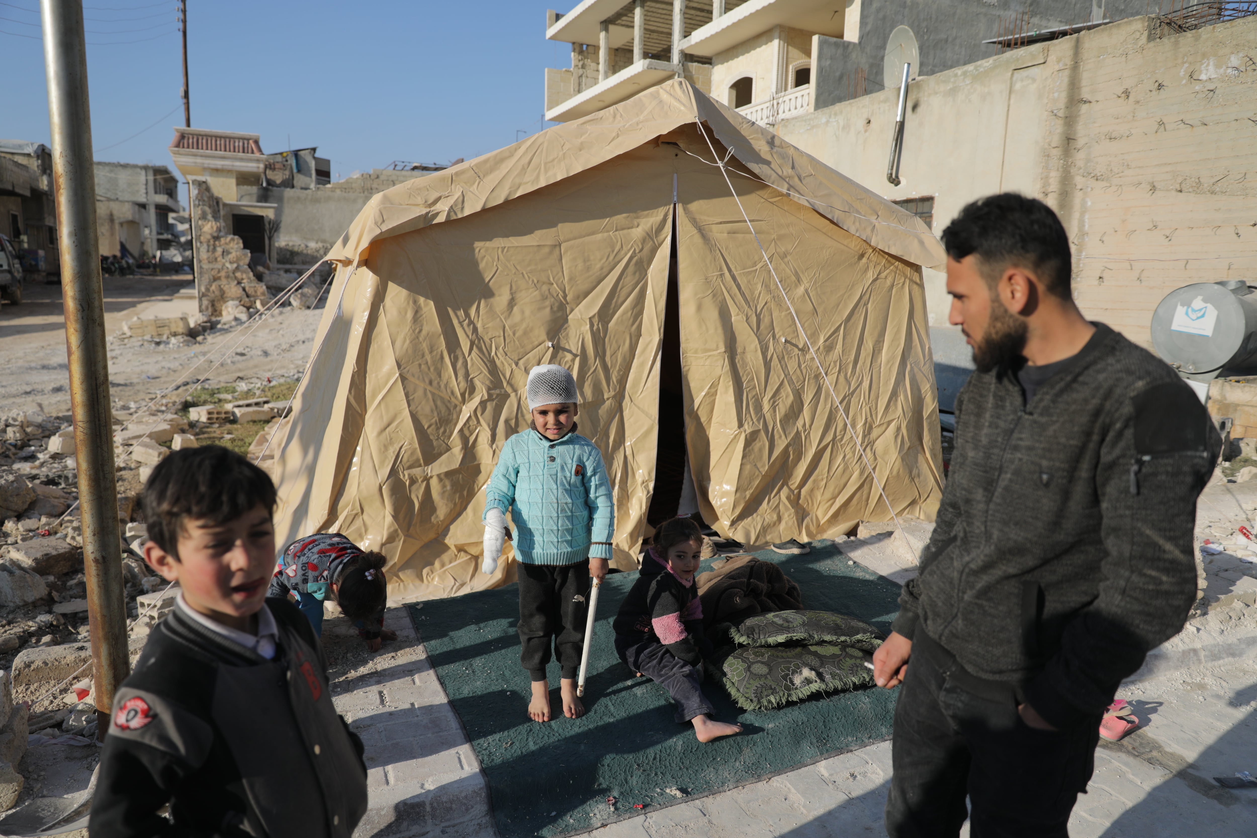 Musa, su padre Ahmed y su hermano Ammar frente a la tienda en la que se refugiaron después del terremoto de Turquía y Siria