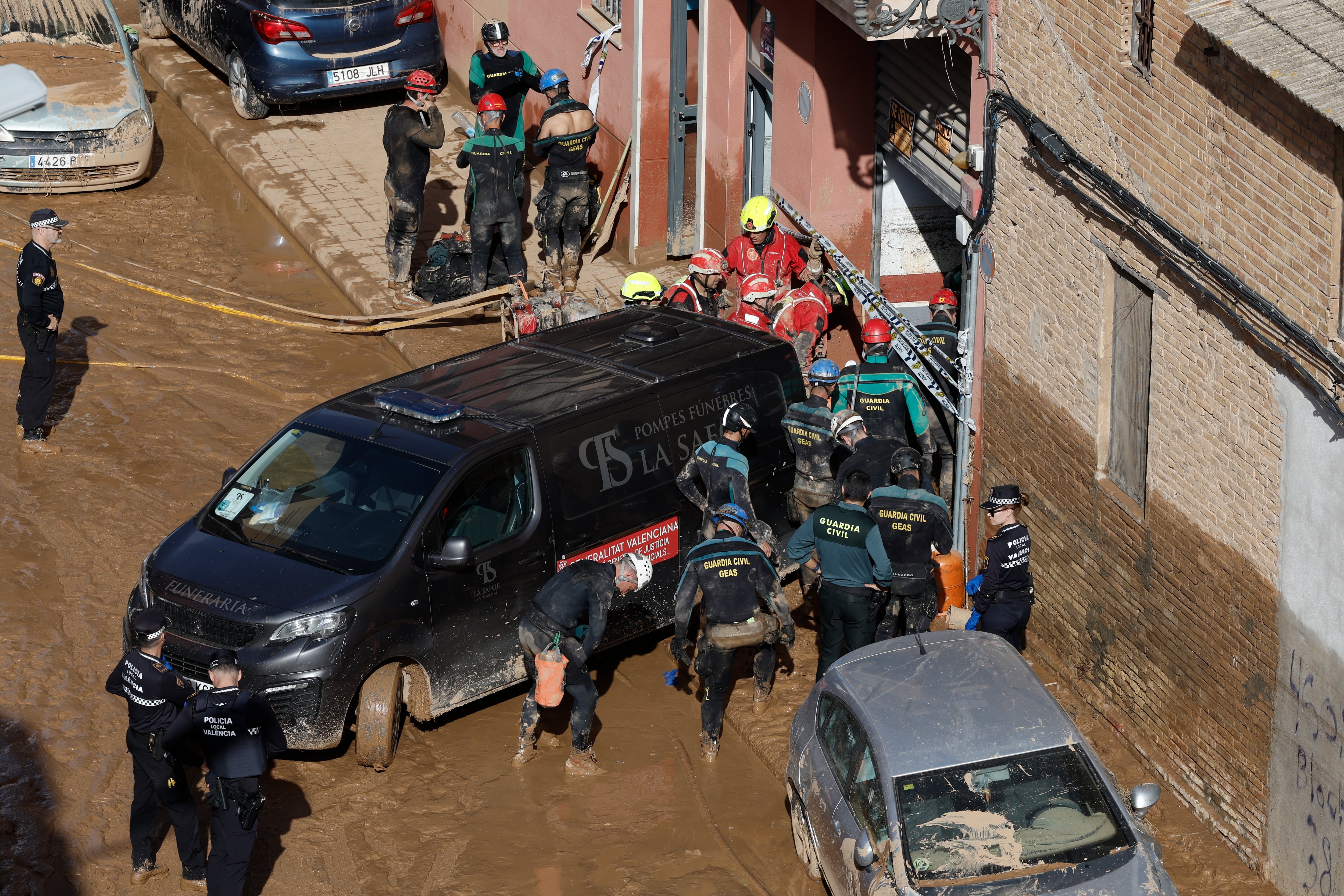 Guardias civiles y policías locales acceden al interior de un garaje en el barrio valenciano de La Torre, en búsqueda de posibles fallecidos