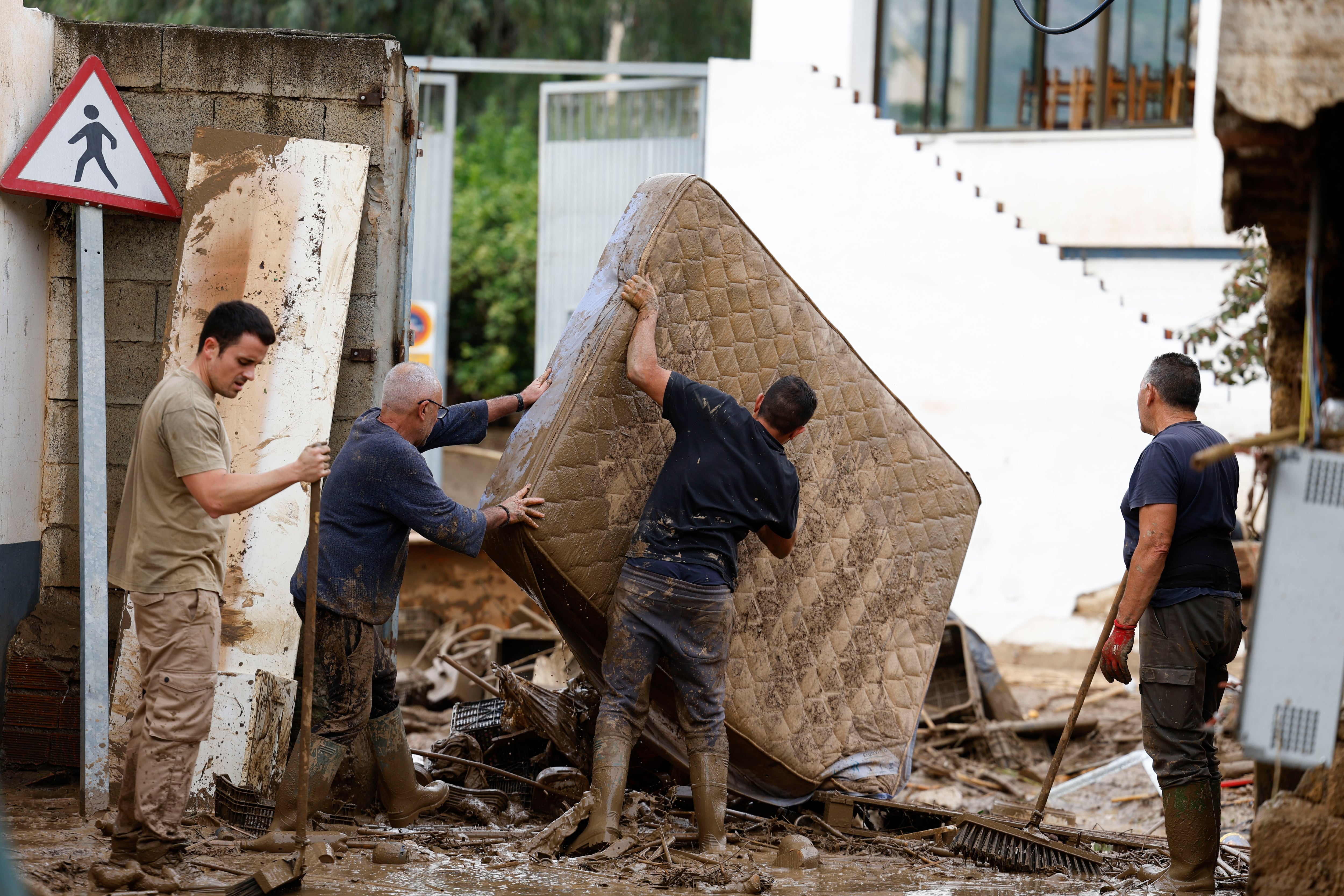 Vecinos sacan a la calle enseres dañados por las inundaciones en la localidad malagueña de Benamargosa.