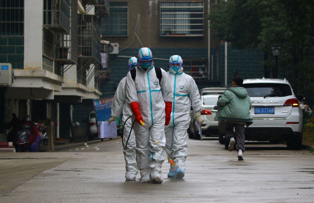 Un grupo de trabajadores del departamento local de control y prevención de enfermedades en trajes protectores desinfectan un área residencial después del brote de un nuevo coronavirus, en la localidad china de Ruichang.