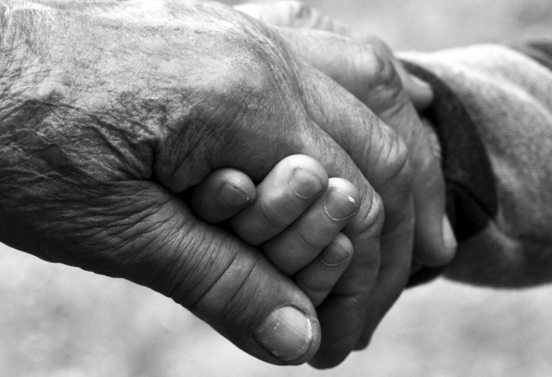 Un abuelo agarra la mano de su nieto