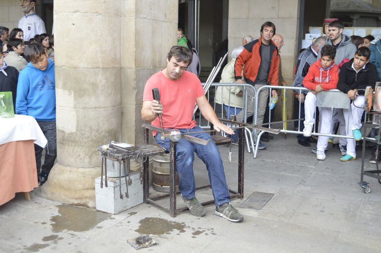 Un artesano del vidrio muestra cómo realiza su oficio ante el público en la Plaza de Navarra 