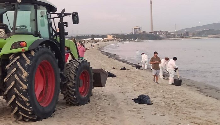 Trabajadores limpiando el vertido en la playa de El Rinconcillo