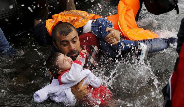 Un refugiado sirio sostiene a su bebé a su llegada a la isla griega de Lesbos tras una travesía en una barcaza.