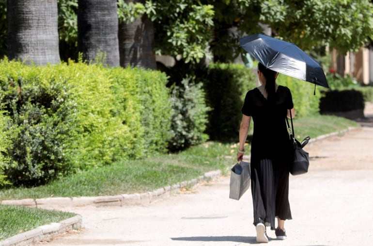 Una mujer se protege con un parasol