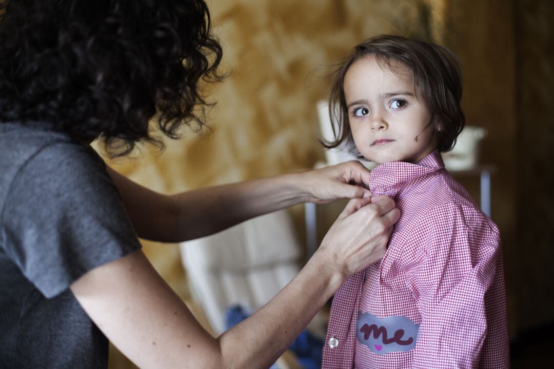 Una niña con la bata para ir a clase. 