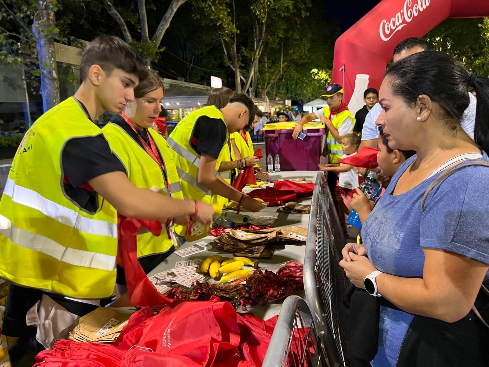 Miembros de la Coordinadora de Peñas entregan a los participantes en el récor su plátano, una bolsa y una pañoleta de fiestas