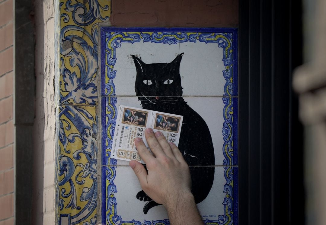 Un hombre pasa dos décimos por el popular azulejo de la administración de loterías &#039;El gato negro&#039;, en Sevilla. 