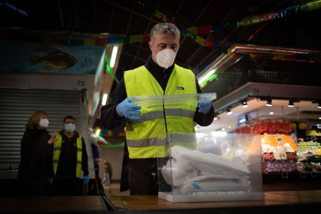 Un operario coloca las urnas y papeletas electorales en una mesa 