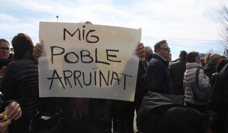 Una dona mostra un cartell on s'hi llegeix 'Mig poble arruïnat' el 6 de març de 2016.