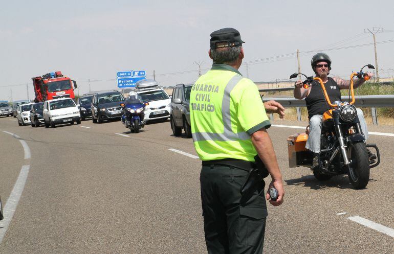 Un motorista pasa junto a un Guardia Civil que regula el tráfico