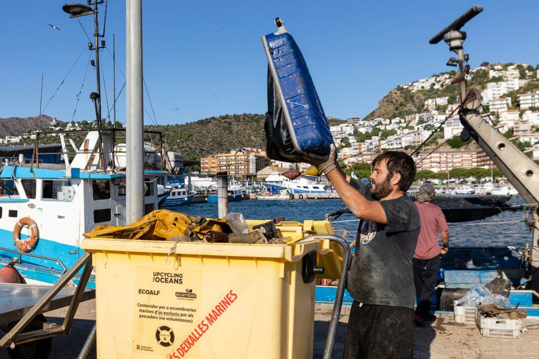 Un pescador buidant alguns dels residus que s&#039;han trobat a alta mar en el Port de Roses