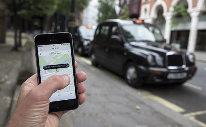 Un usuario utiliza la aplicación Uber ante un taxi en Londres