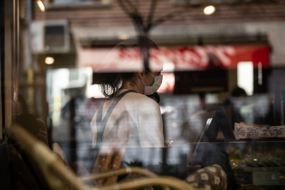 Una trabajadora atiende con una mascarilla protectora durante el primer día laborable de la segunda semana desde que se decretó el estado de alarma en el país a consecuencia del coronavirus, en Barcelona