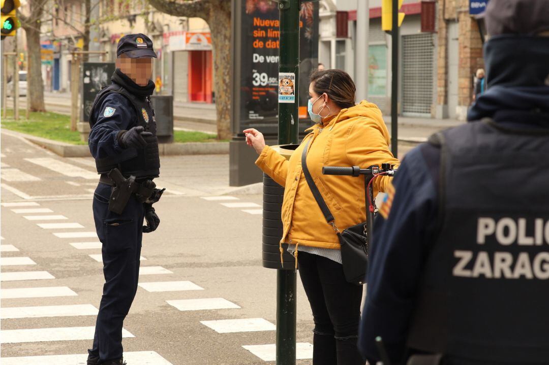 Un policía habla con una mujer con protegida con mascarilla en el tercer día laborable del estado de alarma por coronavirus, en Zaragoza (España), a 18 de marzo de 2020.