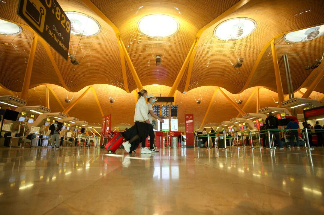 Dos personas caminan con su equipaje en la Terminal T4 del Aeropuerto Adolfo Suárez Madrid-Barajas, en Madrid (España)